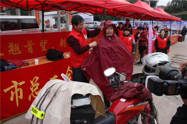 梧州市總工會(huì)的黨員義工們?cè)谑袞|出口春運(yùn)服務(wù)站助力“摩托大軍”平安返鄉(xiāng)，幫助他們檢查車(chē)輛和行李，穿上雨衣。--黃賀峰攝.j